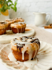 Cinnamon roll muffin topped with vanilla glaze on a plate