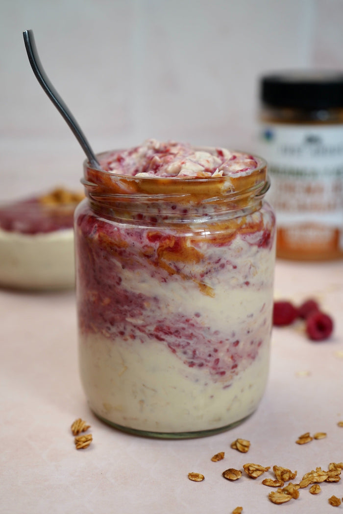 PB&J oats layered with peanut butter and raspberry jam in a glass jar